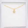 A delicate gold chain necklace with a small heart-shaped pendant set with a clear gemstone, presented inside a white jewelry box.