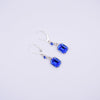 A pair of silver leverback drop earrings featuring rectangular blue crystal charms and small round blue accent beads, displayed on a clean white background.