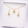 A gold heart jewelry set consisting of a necklace and two matching drop earrings, displayed inside a white gift box on a white background.